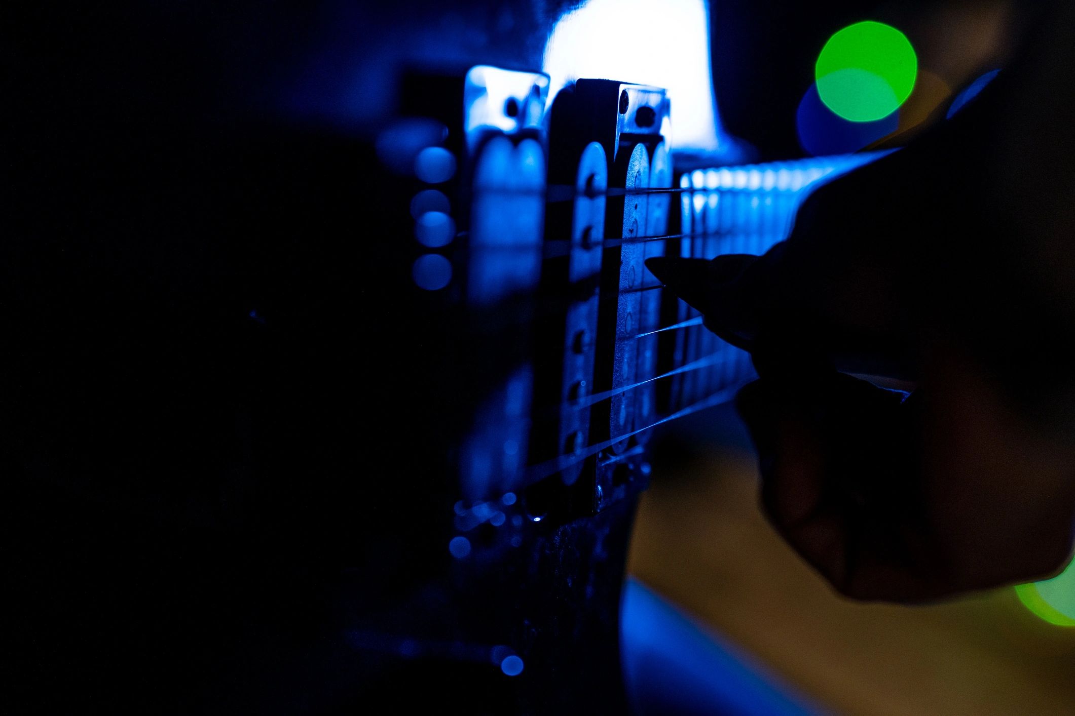 Close-up of a guitar being strummed with blue stage lighting