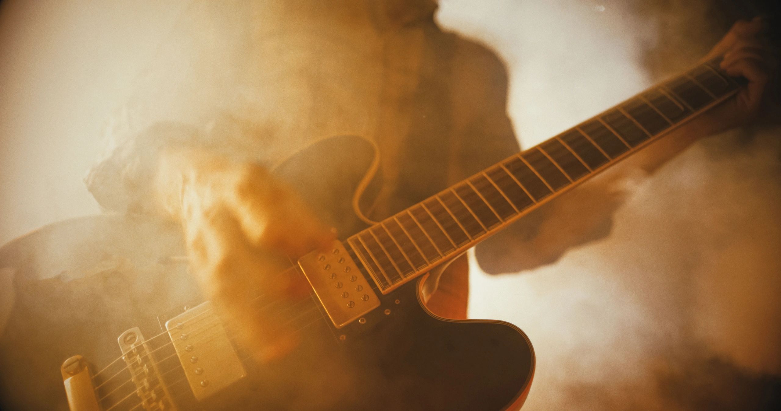 Guitarist performing live with smoke and colored lights